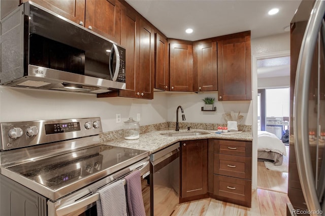 kitchen with light stone countertops, light wood-style flooring, recessed lighting, a sink, and stainless steel appliances