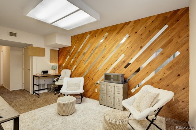 living area featuring visible vents, wood walls, and carpet