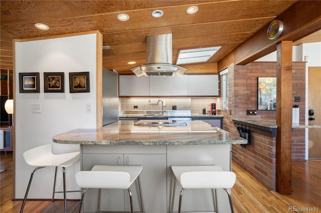 1400 E Bates Ave, Englewood, CO 80113 - kitchen featuring light wood-style flooring, island exhaust hood, a sink, backsplash, and recessed lighting