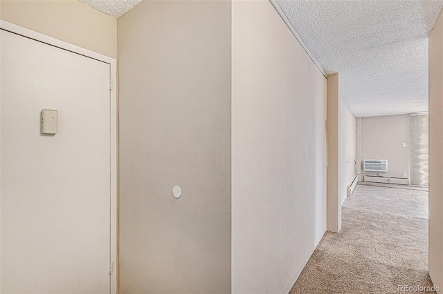 hallway with a wall mounted air conditioner, light colored carpet, a baseboard radiator, and a textured ceiling