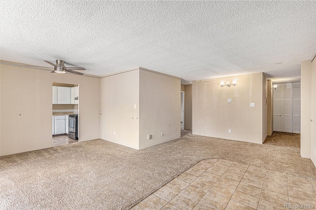 spare room with ceiling fan, a textured ceiling, and light carpet