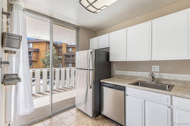 kitchen featuring appliances with stainless steel finishes, sink, light tile patterned floors, and white cabinets