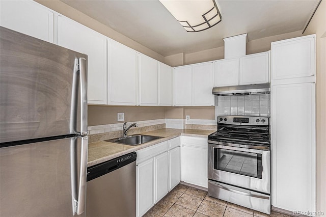 kitchen with appliances with stainless steel finishes, white cabinetry, sink, and light tile patterned flooring