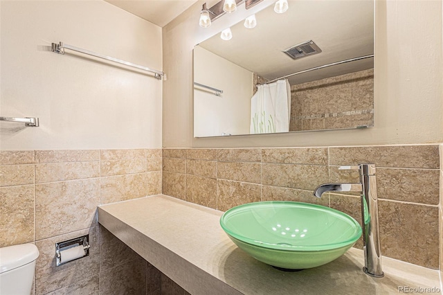 bathroom featuring tile patterned flooring, toilet, sink, tile walls, and a shower with shower curtain