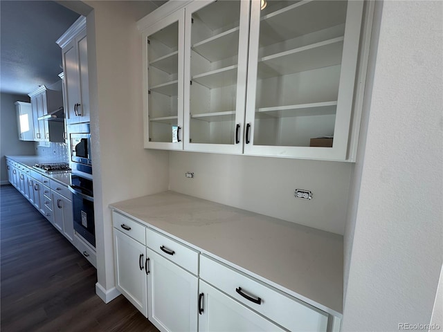 bar with white cabinets, dark hardwood / wood-style floors, light stone countertops, and appliances with stainless steel finishes