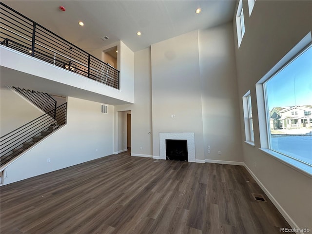 unfurnished living room with dark wood-type flooring and a towering ceiling