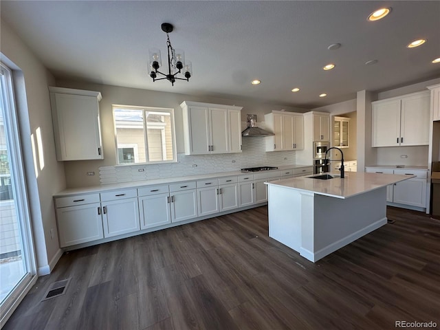 kitchen featuring hanging light fixtures, white cabinets, dark hardwood / wood-style floors, gas stovetop, and wall chimney range hood