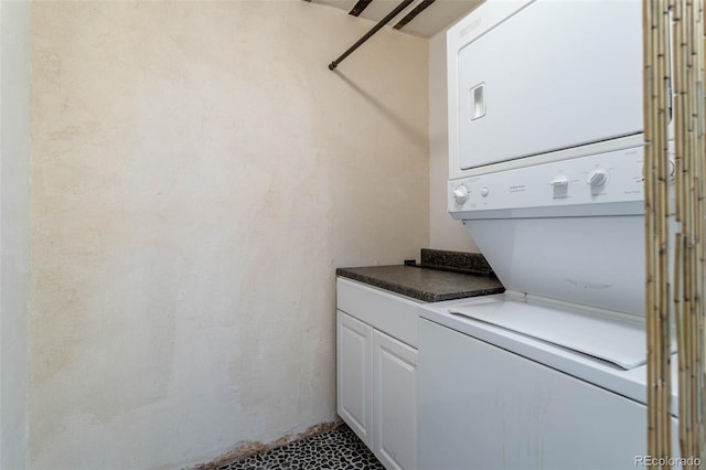 clothes washing area with stacked washer / dryer and cabinets