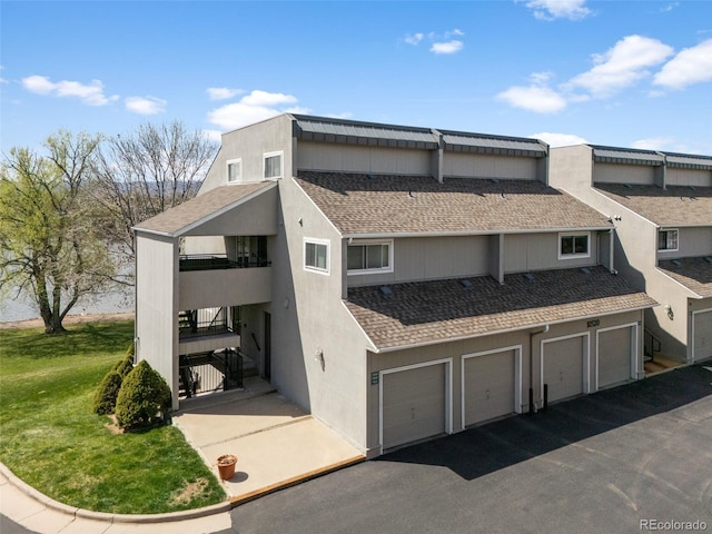 10520 W Jewell Ave Unit 102, Lakewood, CO 80232 - view of front of house featuring a garage, roof with shingles, stucco siding, and aphalt driveway