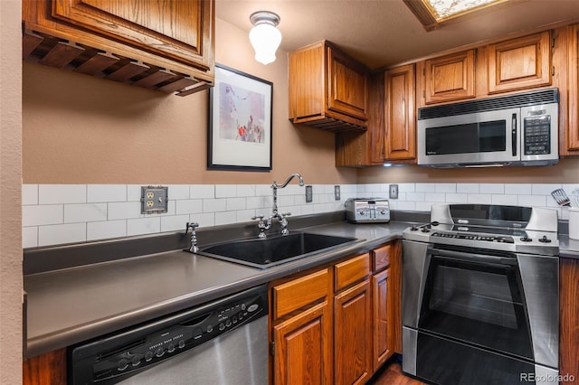 10520 W Jewell Ave Unit 102, Lakewood, CO 80232 - kitchen featuring a sink, dark countertops, backsplash, brown cabinetry, and appliances with stainless steel finishes