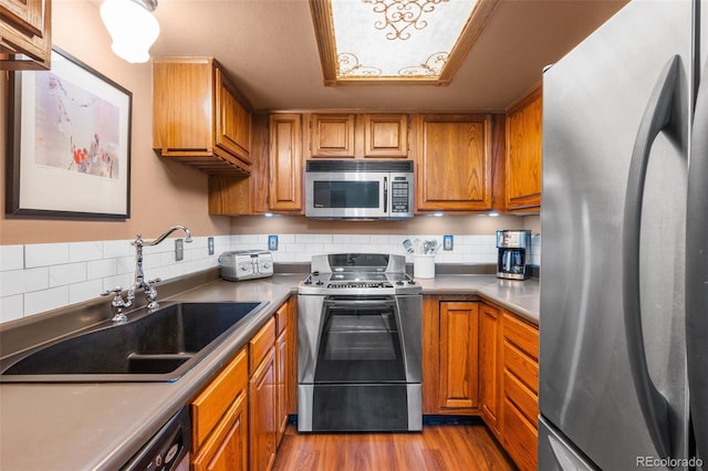 10520 W Jewell Ave Unit 102, Lakewood, CO 80232 - kitchen with wood finished floors, a sink, brown cabinets, and appliances with stainless steel finishes