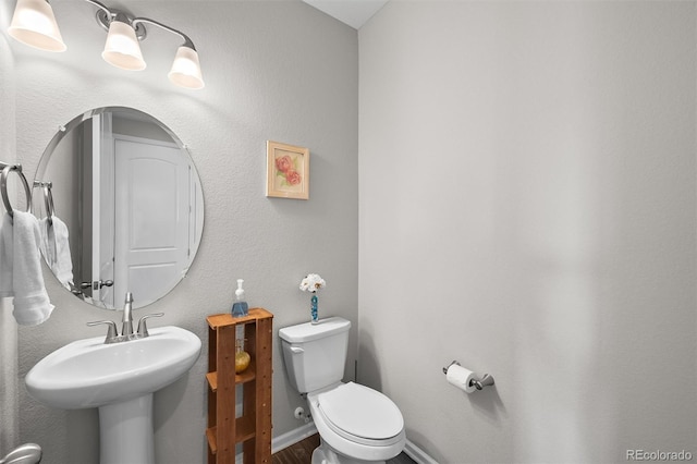 bathroom with toilet, baseboards, and a sink