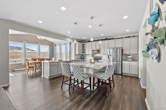 kitchen with a kitchen island, a sink, stainless steel appliances, and dark wood-style flooring