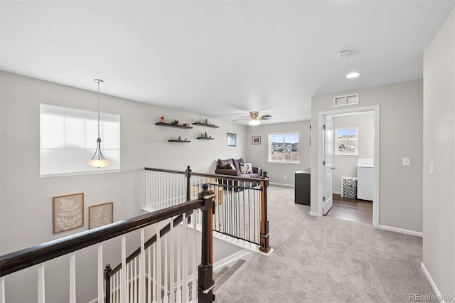 hall featuring visible vents, an upstairs landing, baseboards, and carpet flooring