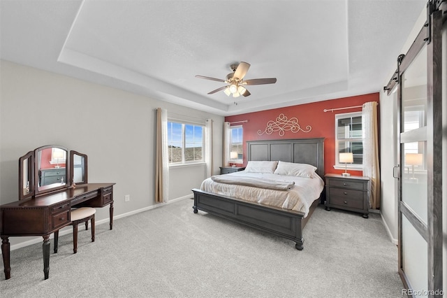 bedroom featuring ceiling fan, baseboards, a barn door, light carpet, and a raised ceiling