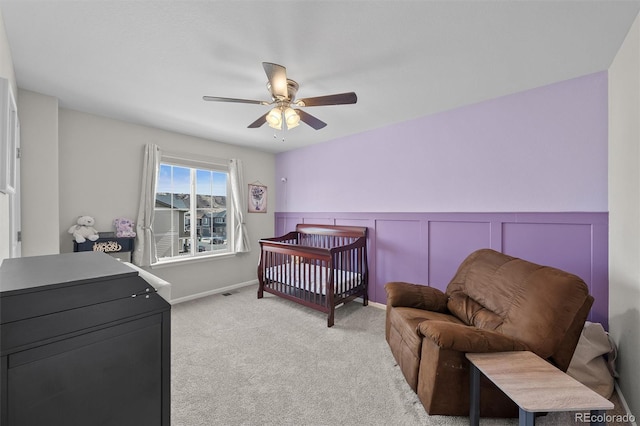 bedroom with wainscoting, visible vents, light colored carpet, and a ceiling fan