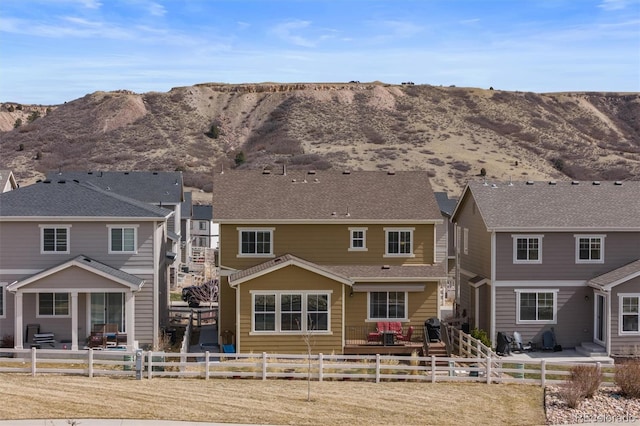 back of house featuring a fenced front yard, a patio area, and a mountain view