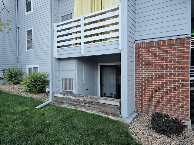 view of exterior entry featuring a balcony and brick siding