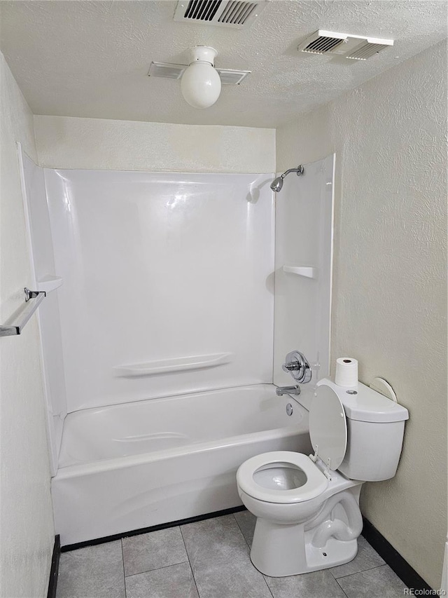 full bathroom with toilet, tile patterned floors, a textured ceiling, washtub / shower combination, and a textured wall
