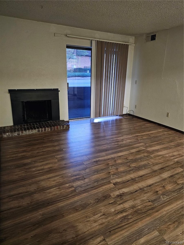 unfurnished living room with wood finished floors, a fireplace, a textured ceiling, and baseboards