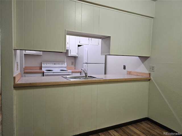 kitchen with white appliances, a sink, a peninsula, and dark wood-type flooring
