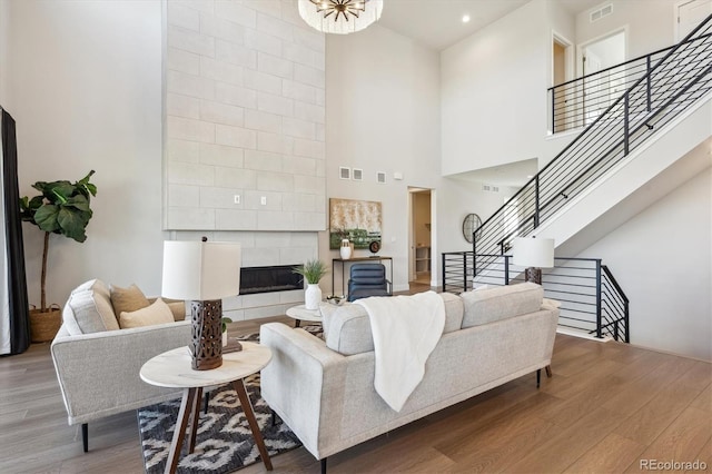 14337 Shasta Daisy Pt, Parker, CO 80134 - living room featuring wood finished floors, a towering ceiling, stairs, and a tile fireplace