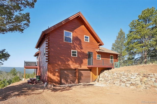 102 Douglas Fir Ln, Woodland Park, CO 80863 - back of property with dirt driveway, an attached garage, a wooden deck, and log siding