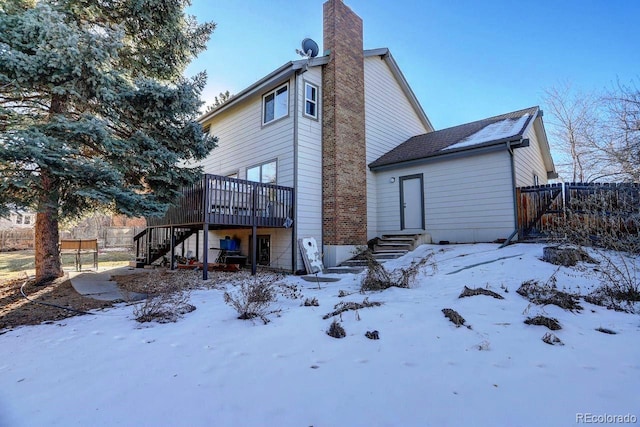 snow covered back of property featuring a deck