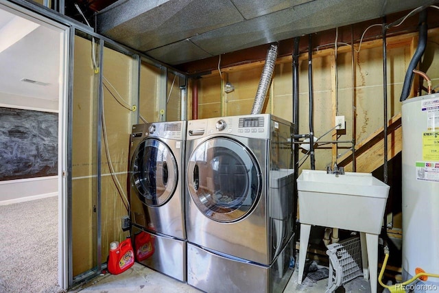 clothes washing area with washer and dryer and gas water heater