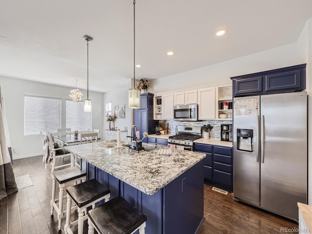 kitchen with sink, hanging light fixtures, a center island with sink, a kitchen breakfast bar, and stainless steel appliances