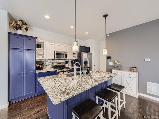 kitchen with hanging light fixtures, stainless steel appliances, a kitchen breakfast bar, and a center island with sink