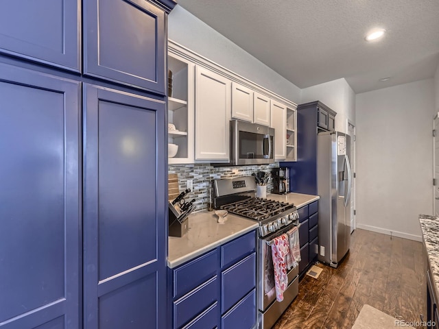 kitchen with blue cabinets, white cabinetry, appliances with stainless steel finishes, dark hardwood / wood-style floors, and backsplash