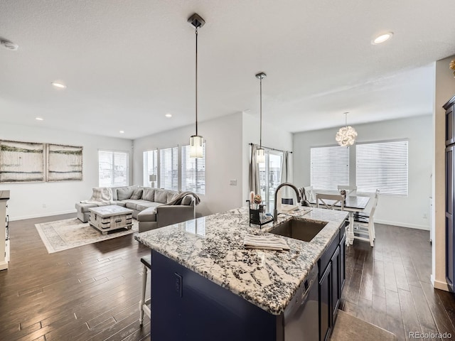 kitchen with sink, a kitchen island with sink, hanging light fixtures, dark hardwood / wood-style floors, and stainless steel dishwasher