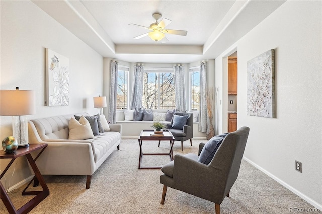 sitting room featuring light carpet, ceiling fan, and a tray ceiling