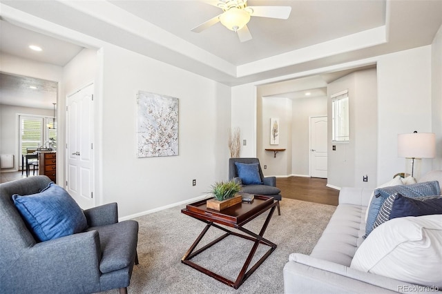 living room featuring a tray ceiling and ceiling fan