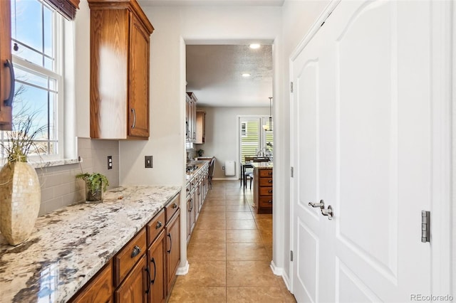 kitchen with light stone counters, light tile patterned floors, decorative backsplash, and a textured ceiling