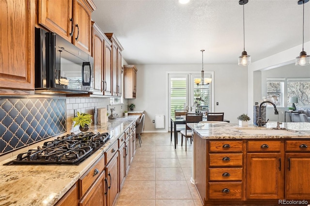 kitchen with light tile patterned flooring, pendant lighting, sink, decorative backsplash, and stainless steel gas cooktop