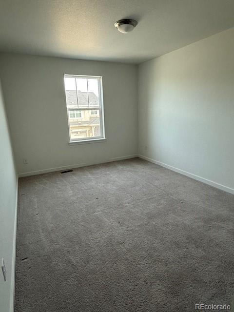 unfurnished room with carpet flooring, baseboards, and visible vents