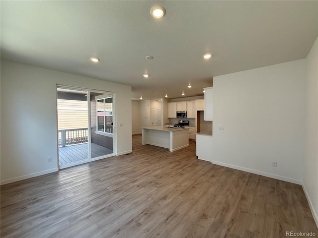 9041 Redfield Ln, Parker, CO 80134 - unfurnished living room featuring baseboards, light wood-type flooring, recessed lighting, and a sink