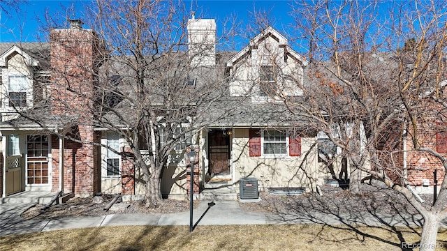 view of front facade featuring a chimney and central air condition unit