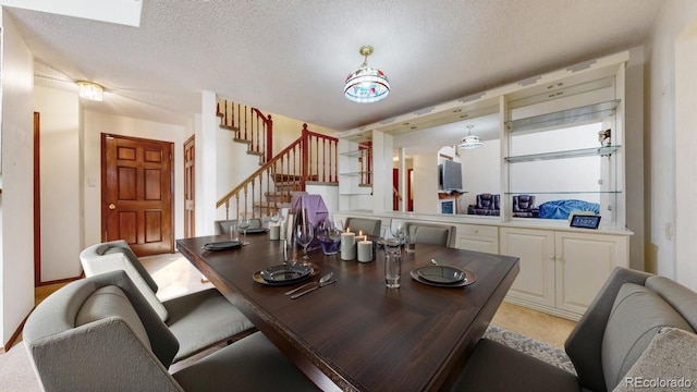 dining space featuring light carpet, stairway, and a textured ceiling