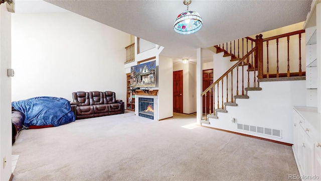 living area with a tile fireplace, carpet floors, visible vents, baseboards, and stairs