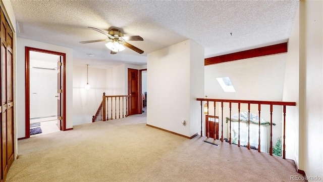 spare room with a skylight, a baseboard radiator, ceiling fan, beamed ceiling, and carpet