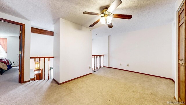 carpeted spare room featuring a textured ceiling and baseboards