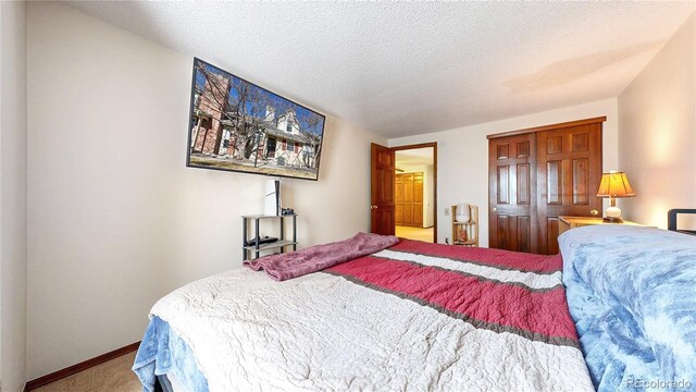 bedroom featuring a textured ceiling, a closet, carpet, and baseboards