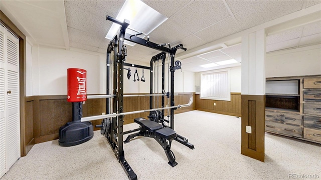 workout room with a wainscoted wall, wood walls, and a paneled ceiling