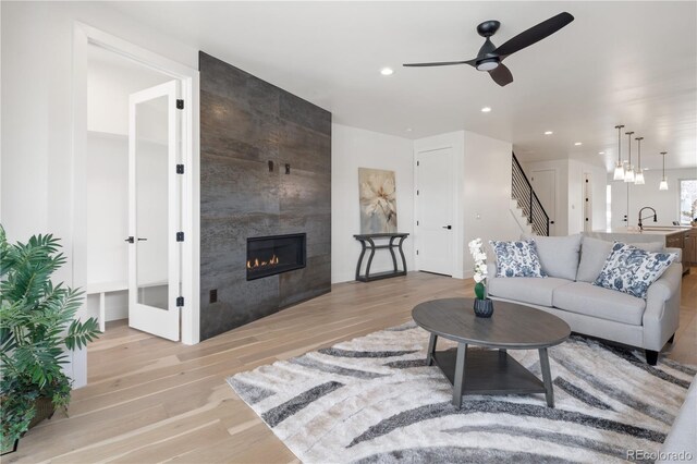 1953 W 47th Ave, Denver, CO 80211 - living area featuring stairs, ceiling fan, recessed lighting, a tiled fireplace, and light wood finished floors
