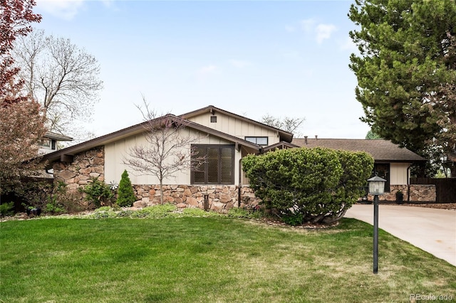 view of front of home with concrete driveway, a front yard, and stone siding