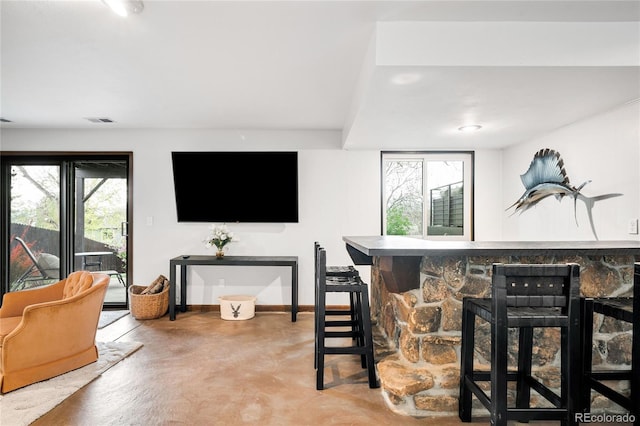 bar featuring finished concrete flooring, baseboards, a bar, and visible vents