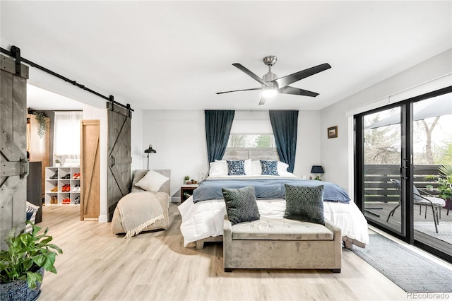 bedroom with a barn door, a ceiling fan, wood finished floors, and access to exterior